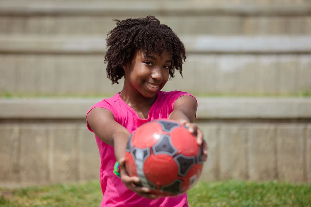 Bambina sorridente che porge il pallone verso la telecamera