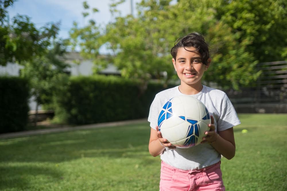 Bambina sorridente con il pallone tra le mani
